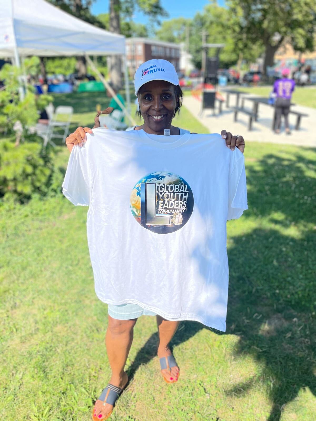 A community representative holding a shirt bearing the Global Youth Leaders for Humanity logo at a Detroit event